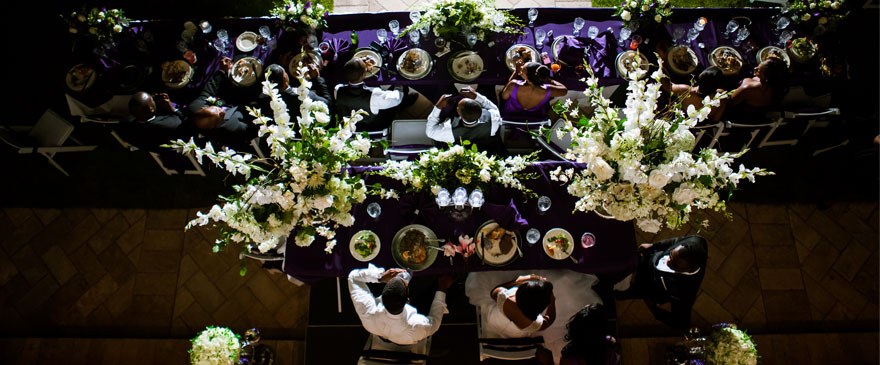 Overhead view of a wedding head table with white floral arrangements and purple linens