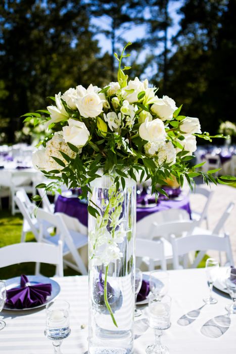 Tall glass centerpiece of white roses on a reception table