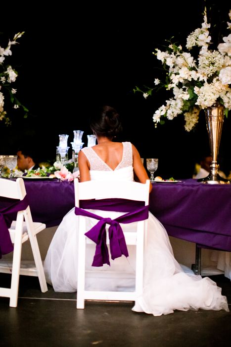 Bride seated at a chair tied with a purple sash