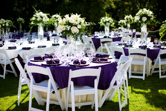 Round reception tables with purple linens on the lawn