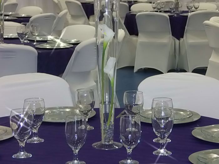 Indoor reception with purple tablecloths and white chair covers