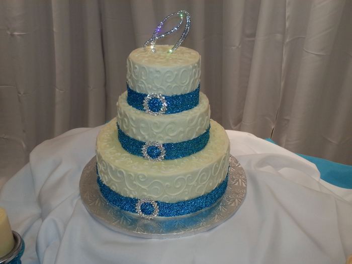 Three-tier white wedding cake with blue ribbon